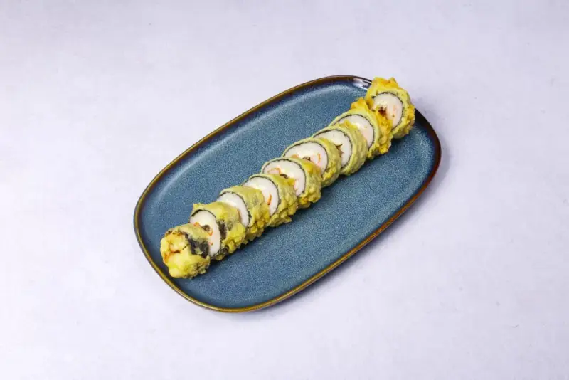 Chrupiące rolki sushi z rybą w tempurze, ułożone na niebieskim talerzu.
