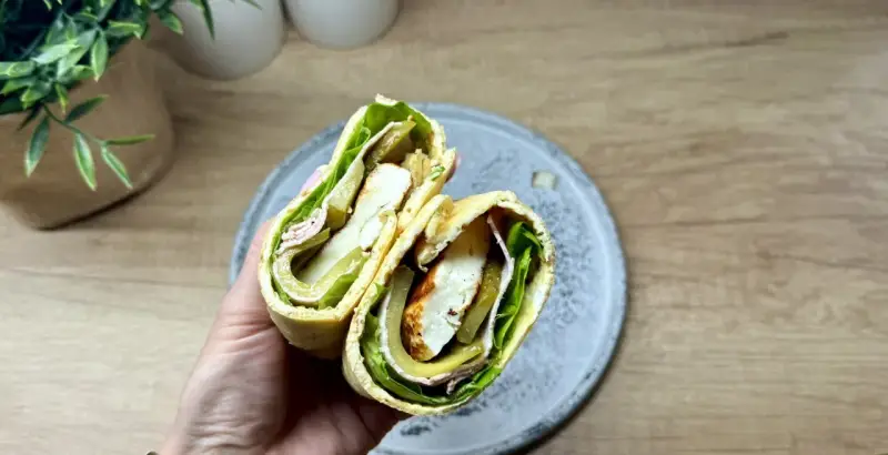 Pyszny wrap wege z serem halloumi, sałatą, ogórkiem kiszonym i oliwkami. Idealny na szybki lunch.